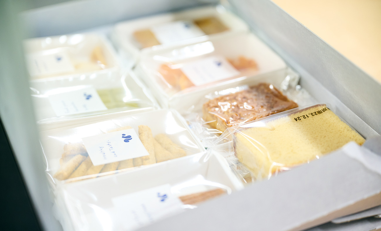 ユーザーの好みに合わせたお菓子を工場でスタッフがセレクト、箱詰めしている