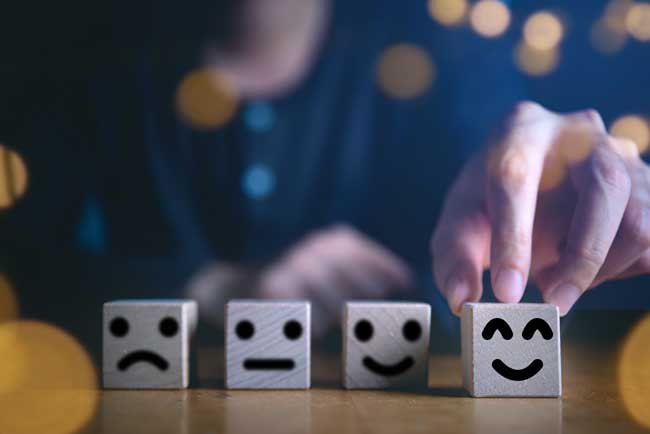 Businessman hand holding touching smile face or happy face which print screen on wooden cube block, Business service rating , Satisfaction concept.Selection & Choosing emotion or mood concept.