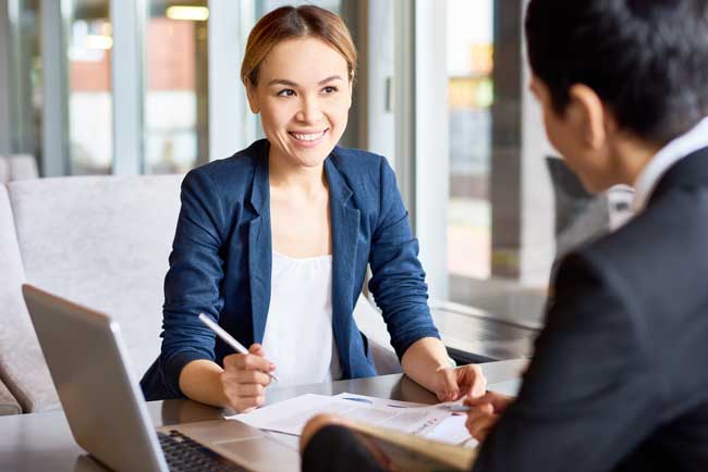Attractive Asian entrepreneur discussing details of mutually beneficial cooperation with her female business partner while having negotiations at cozy cafe