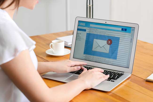 Young woman with laptop checking her e-mail in office
