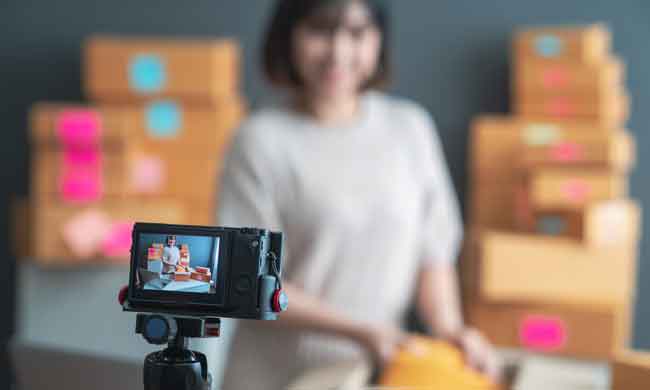 Beautiful asian woman blogger showing clothes in front of camera to recording vlog video live streaming at her shop