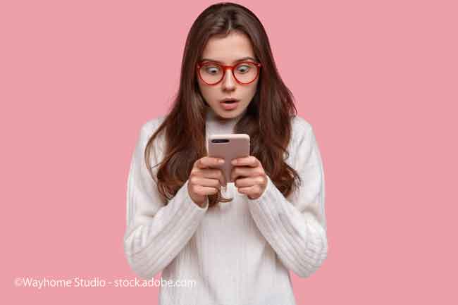 lady stares at cell phone with surprised expression wears casual white sweater, reads shocking news on internet website