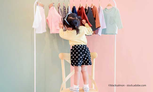 Two Years Old Child Choosing her own Dresses from Kids Cloth Rack