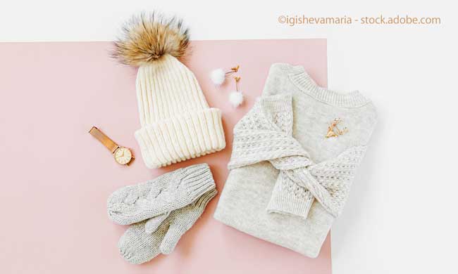 Gray warm knitted sweater with winter hat, mittens on pale pink background. Women's stylish winter clothes