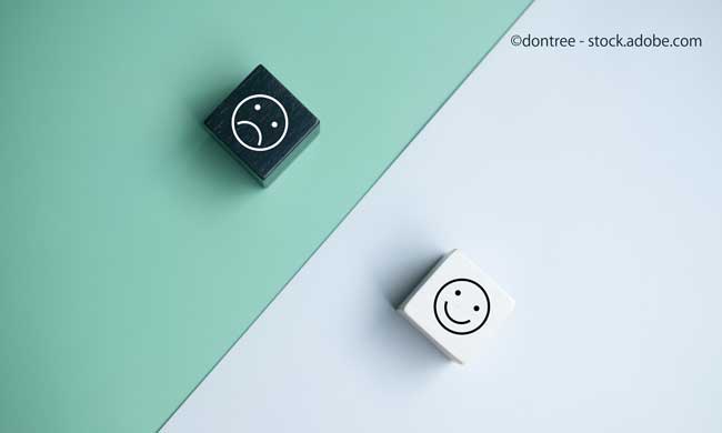 Smiley face and blurred sad face icon on wood cube