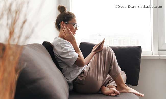 Image of concentrated woman using cellphone while sitting on sofa
