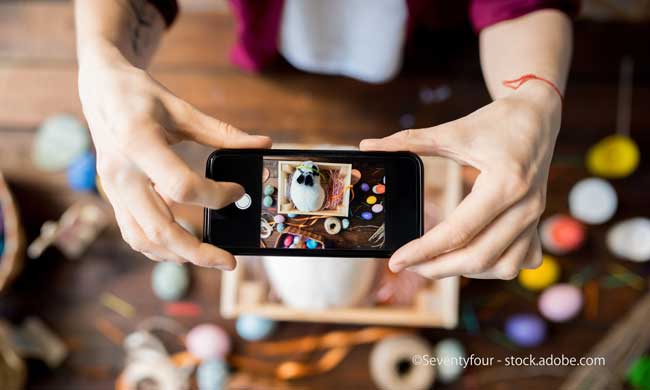 Top view close up of unrecognizable woman taking picture of Easter set up via mobile phone, copy space
