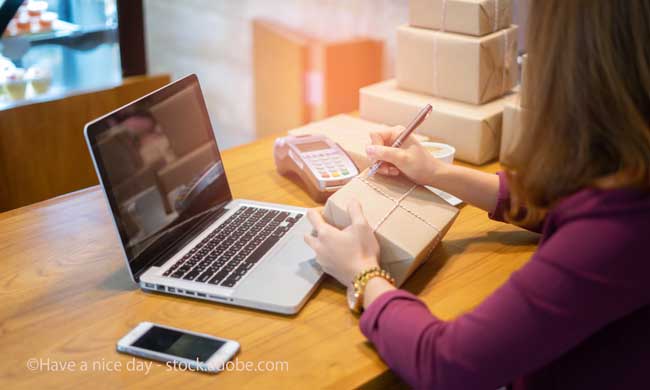 Shipping shopping online ,young start up small business owner writing address on cardboard box at workplace