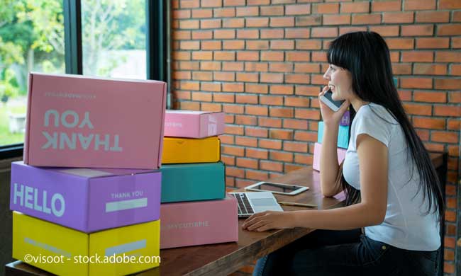 ネットショップの箱が多数ある部屋にいる女性