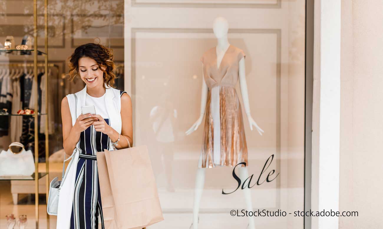 店前でスマートフォンを操作する女性