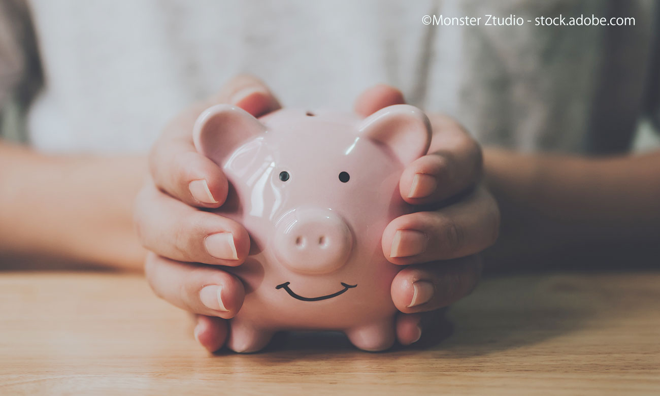 Man hand holding piggy bank on wood table, Save money